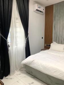 a bedroom with a white bed and a window at Ehi-Mega Luxury Hotel and Apartment in Abuja
