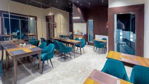 a restaurant with wooden tables and blue chairs at The Royal Luxe in Kolur