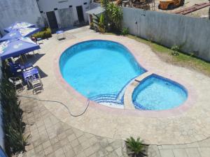 a large swimming pool in a yard with an umbrella at Hotel Monte Verde in Beira