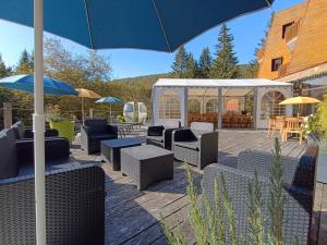 a patio with chairs and tables and an umbrella at Gîte les Égravines in Mijoux