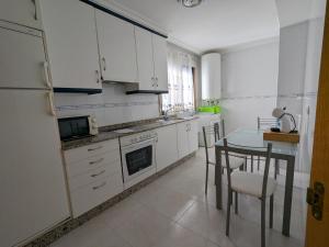 a kitchen with white cabinets and a table and a dining room at L&C Codesal in Sanxenxo