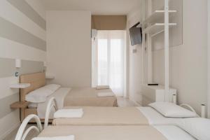 a white room with three beds and a television at Hotel Leon D'oro in Cattolica