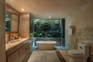 a bathroom with a bath tub and a fishtank at Aksara Ubud in Ubud +42 photos