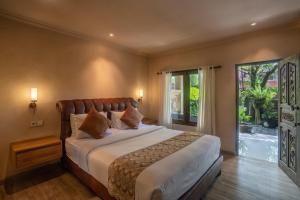 a bedroom with a large bed and a large window at Aksara Ubud in Ubud