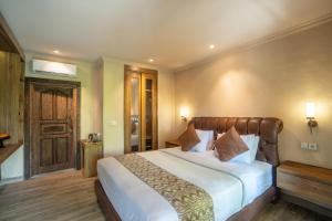 a bedroom with a large bed with white sheets at Aksara Ubud in Ubud