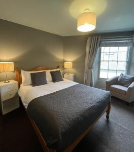 a bedroom with a bed and a chair and a window at Smugglers Hotel in Brixham