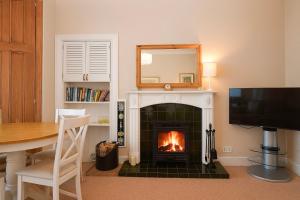 a living room with a fireplace with a table and a television at Kames View Apartment in Tighnabruaich