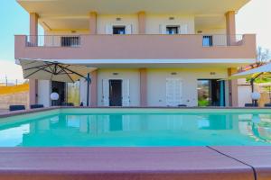 a swimming pool with an umbrella and a building at Riflessi D'aurora in Castelsardo
