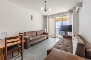 a living room with a couch and a tv at Beachfront Apartment with Pool Access by PikHost in Lezhë