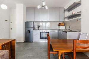 a kitchen with white cabinets and a wooden table at Beachfront Apartment with Pool Access by PikHost in Lezhë