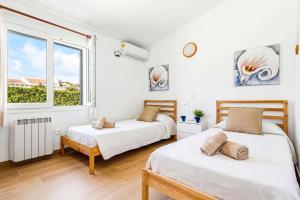 two beds in a white room with a window at Villa Adelaide by Villa Plus in Sant Lluis