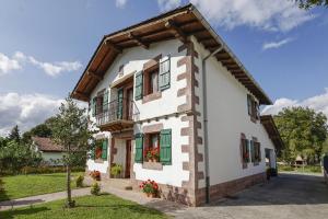 a white house with green windows and a balcony at LOPENEA Baztan in Garzáin