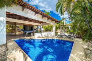 an outdoor swimming pool with a hammock and a house at Villa Sol 23 in Playa Hermosa