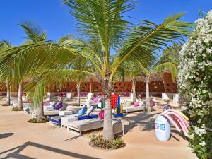 a resort with lounge chairs and a palm tree at Movenpick Resort Lamantin Saly in Saly Portudal