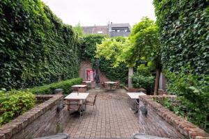 a patio with tables and benches in a garden at Hotel De Groene Hendrickx in Hasselt