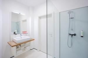 a white bathroom with a sink and a shower at SHOME Hotel Graz I Self-Check-In I Free Parking in Graz