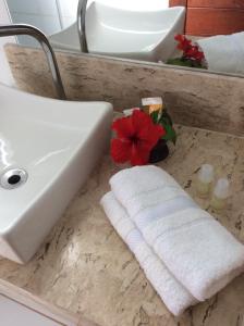 a bathroom sink with a white towel and a red flower at Pousada Caliandra Pipa in Pipa +38 photos