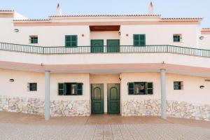 a building with green doors and a balcony at BLUESEA Cabo de Baños in Cala en Blanes