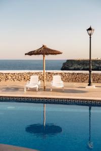 two chairs and an umbrella next to a swimming pool at BLUESEA Cabo de Baños in Cala en Blanes