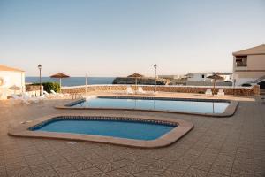 a swimming pool in a patio with the ocean in the background at BLUESEA Cabo de Baños in Cala en Blanes +16 photos
