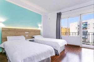 two beds in a room with a large window at BLUESEA Torremolinos Centro in Torremolinos +4 photos