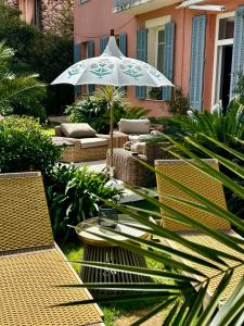 a patio with a table and an umbrella and chairs at Un palmier à sa fenêtre in Grasse