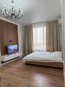 a bedroom with a bed and a tv and a chandelier at Жк Берекелы in Almaty