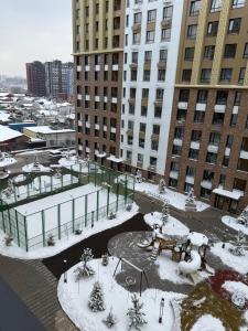 a courtyard covered in snow in a city with tall buildings at Жк Берекелы in Almaty +2 photos