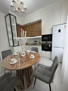 a kitchen with a wooden table with chairs and a dining room at Жк Берекелы in Almaty