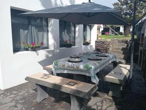 a table with an umbrella and two benches at Surf & Guest Lorena´s House in Ribeira Grande