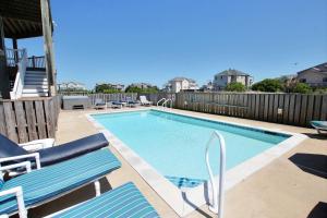 a swimming pool with two lounge chairs next to a fence at Buhlers Day Off in Corolla