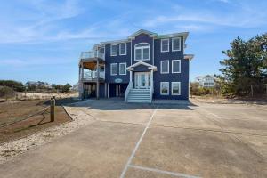 a large blue house with a driveway in front at Buhlers Day Off in Corolla