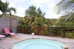 a swimming pool on a wooden deck with pink chairs at Kaz Manga Rose in Deshaies