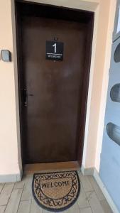 a brown door with a welcome sign on it at apartman Stojković - Banja Ždrelo na 10 min in Petrovac na Mlavi