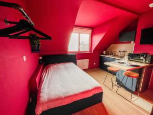 a red room with a bed and a kitchen at La Maison 12 in Valenciennes