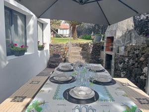 a table with plates and glasses and an umbrella at Surf & Guest Lorena´s House in Ribeira Grande