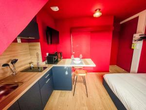 a kitchen with red walls and a sink in a room at La Maison 12 in Valenciennes +35 photos
