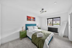 a white bedroom with a bed and a window at Ty Hir in Llanelli