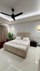 a bedroom with a large bed with a ceiling fan at Luxury Private Room Canal Rd Near Galleria in Faisalabad