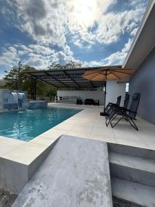 a swimming pool with two chairs and an umbrella at Casa Celeste Rio Grande #2 in Puntarenas