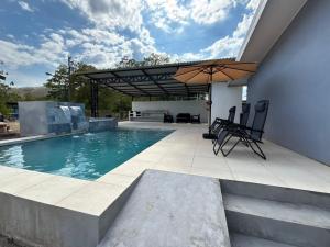 a swimming pool with an umbrella on a patio at Casa Celeste Río Grande in Paquera