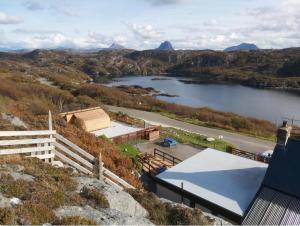 a view of a lake and a building on a hill at The Captains Achmelvich in Lochinver