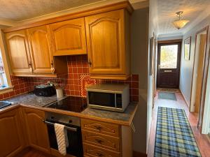 a kitchen with wooden cabinets and a microwave on a counter at The Captains Achmelvich in Lochinver