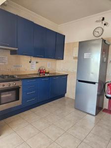 a kitchen with blue cabinets and a stainless steel refrigerator at Zabava Odivelas in Odivelas