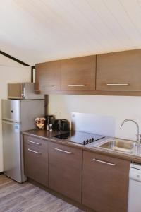 a kitchen with wooden cabinets and a stainless steel refrigerator at Le Clos des Soulacaises in Soulac-sur-Mer