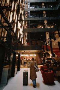 a woman walking through a building with her luggage at Radisson RED Hotel & Radisson RED Apartments, Kraków in Krakow +96 photos
