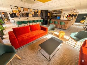 a living room with an orange couch and chairs at Campanile Troyes Sud - Buchères in Troyes