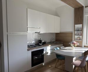 a kitchen with white cabinets and a table with chairs at Maison Louis in Parma