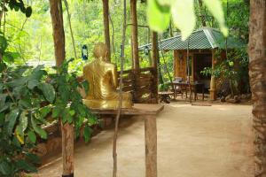 a statue sitting on a bench in a garden at Kandy Eco Retreat in Kandy