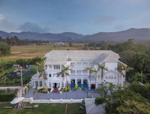a large white house with palm trees in front of it at Lanna Inthan Hotel & Resort in Doi Saket